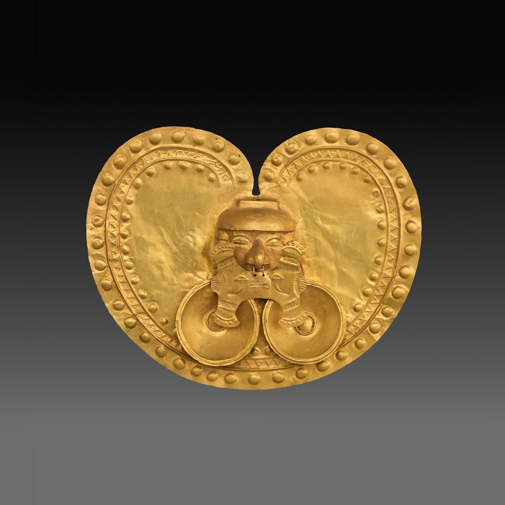 Pectoral de oro en forma de corazón con un rostro