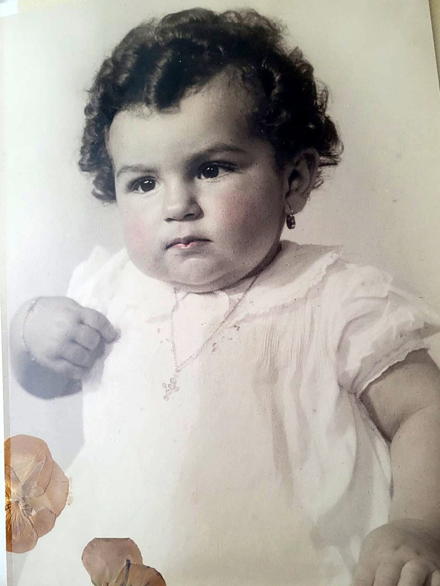 Retrato de estudio de un bebé de pelo crespo, con flores secas sobre la foto