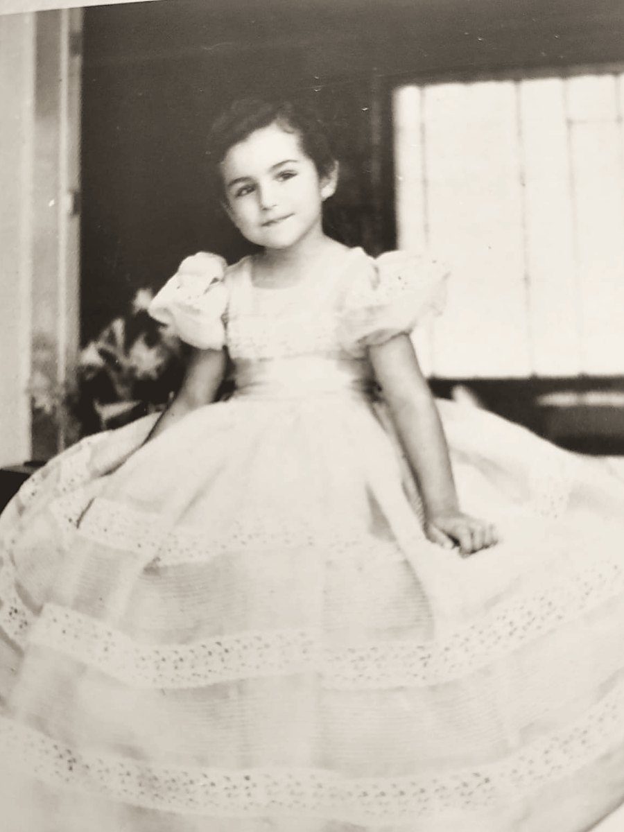 Una niña sentada con un vestido de fiesta de falda amplia
