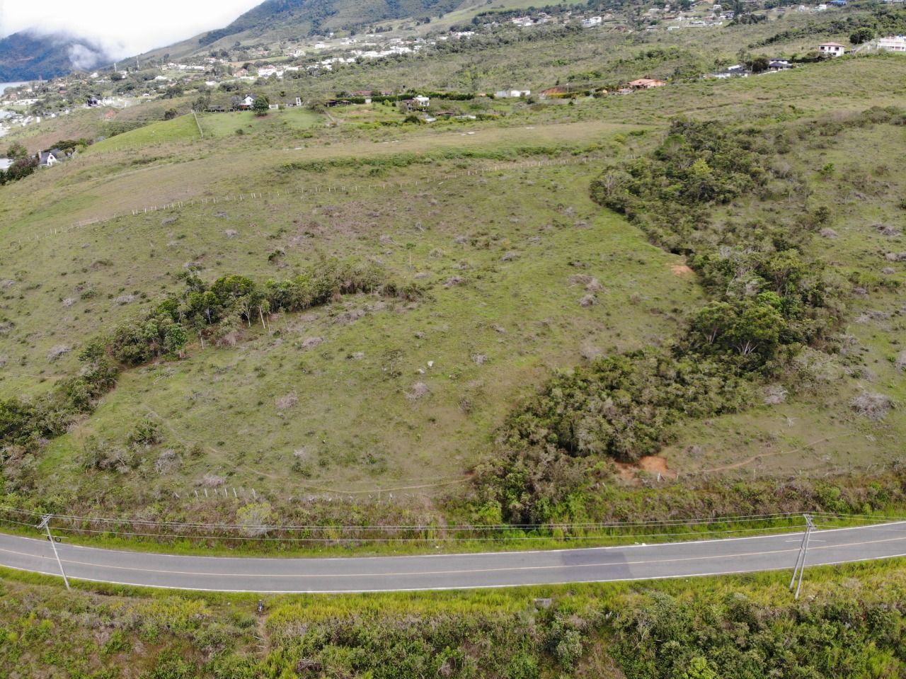 La vía que bordea la ladera, con casas al fondo, vista desde arriba