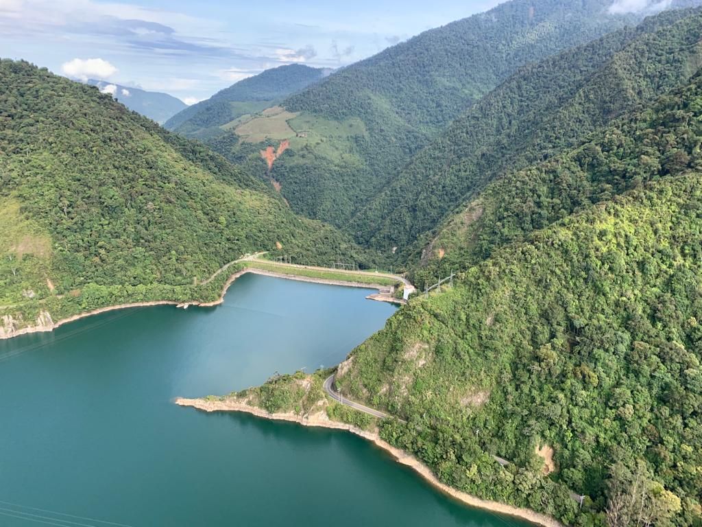 The Lake Calima dam from the air, between forested mountains
