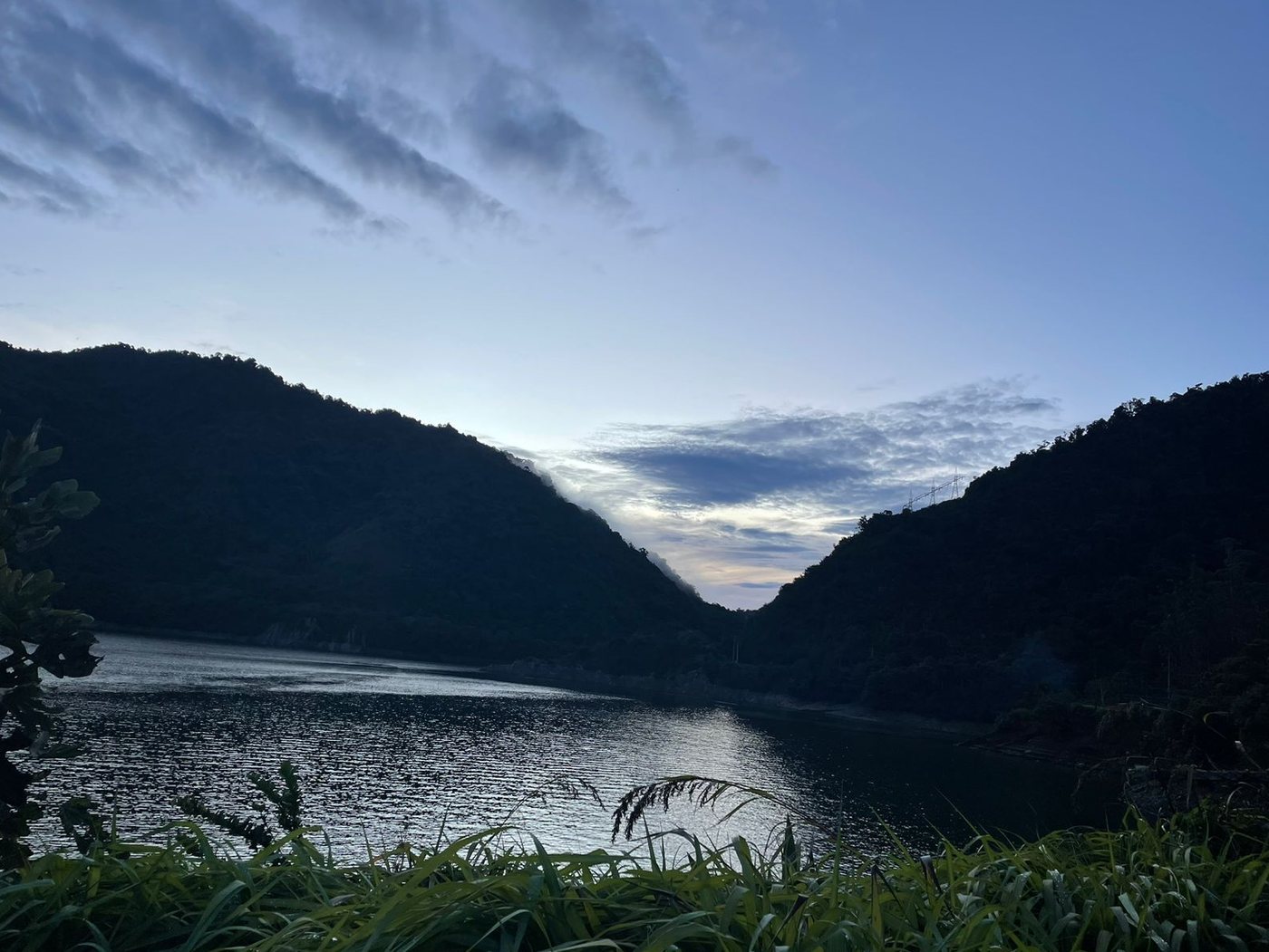 El Lago Calima al amanecer, con el agua quieta entre montañas oscuras