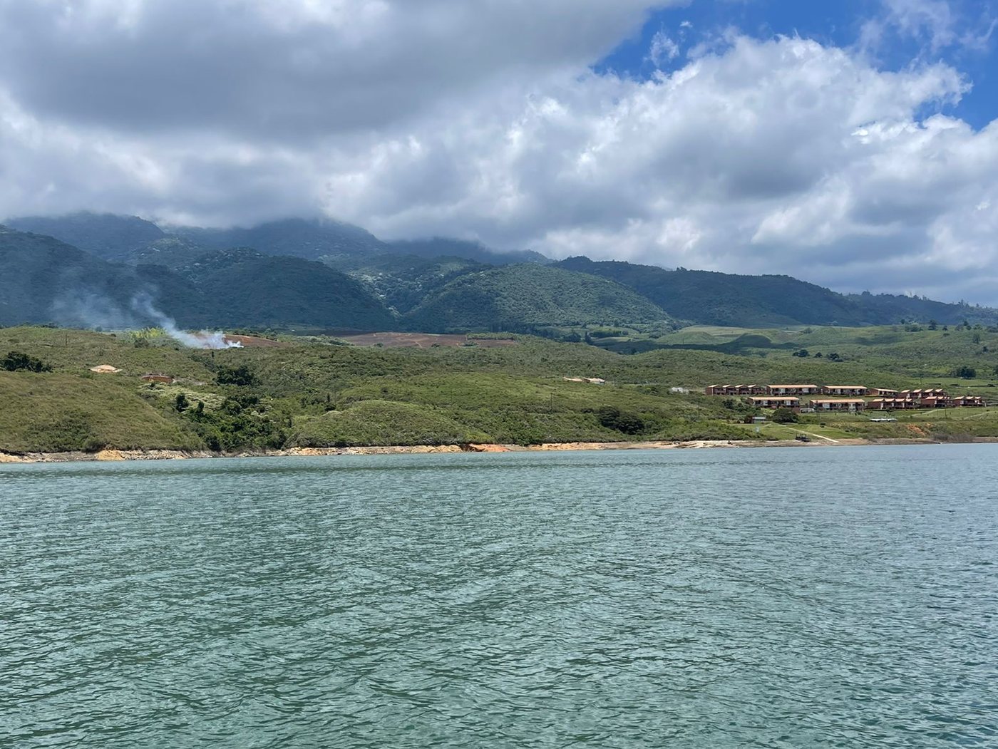 El agua picada del Lago Calima bajo nubes, con lomas verdes al fondo