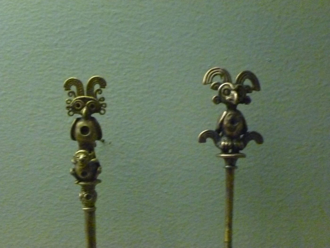 Dos palillos de oro con figuras en la punta, en una vitrina de museo