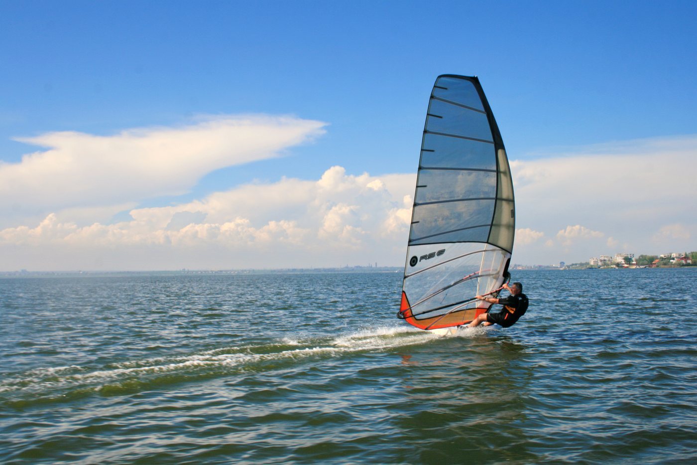Un windsurfista de Fórmula, con tabla ancha y vela grande, planea a toda velocidad