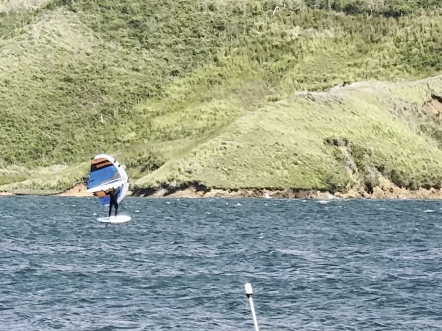 Un deportista con un ala en las manos vuela sobre el agua en una tabla con foil