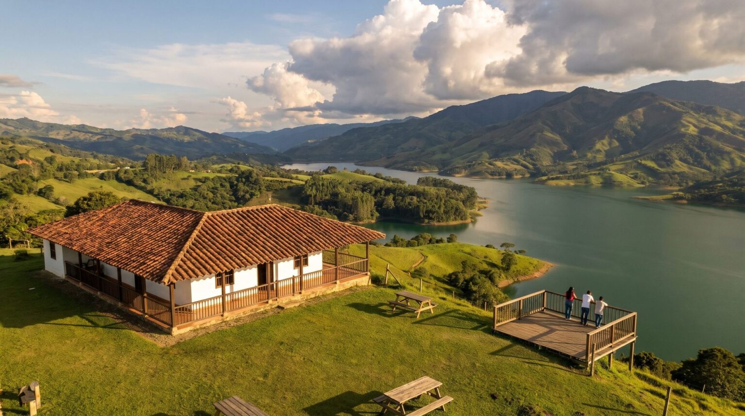 Low clubhouse with white walls, a tile roof and a timber veranda, and a timber lookout at the edge of the high mesa, with an open view over Lake Calima.